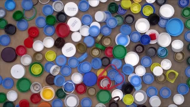Veel kroonkurken. Gebruikte plastic kroonkurken en deksels. Polypropyleen 5, polyethyleen. Afval sorteren en recyclen — Stockvideo