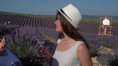 Beautiful girl in a hat with a glass of wine. Outdoor art picnic at the lavender field. Romantic plein air scene on summer day. Open-air party. Rustic landscape. Provence France Europe