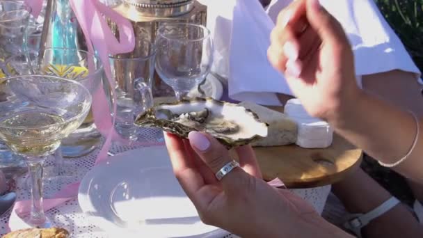 En ung kvinna äter ostron. Utomhus picknick på lavendelfältet med vinost och ostron. Kvinnors fest. Romantisk picknickscen på sommardagen ute i det fria. Provence Frankrike Europa — Stockvideo
