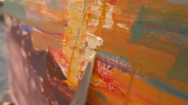 Boya darbelerini ve dokuyu kapat. Ressam, palet bıçağıyla tuvale yağlı boyalarla bir resim çiziyor. Sanat terapisi