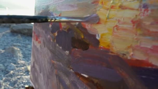 The professional artist paints a sea landscape picture with oil paints on canvas using a brush. Paint strokes and texture close up. Art therapy, hobby — Vídeo de stock