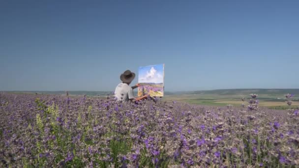 屋外の油絵をプリン空気。田園風景、ラベンダー畑の開花。男性アーティストがイーゼルを使ってキャンバスに絵を描く — ストック動画
