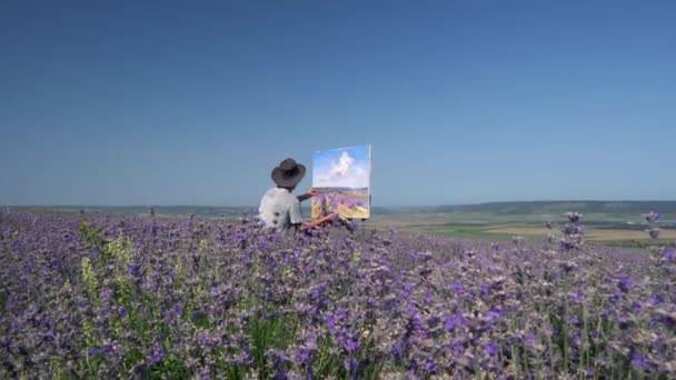 Plein ar ao ar livre pintura a óleo. Paisagem rural, campos de lavanda florescentes. Um artista masculino desenha um quadro em tela usando um cavalete — Vídeo de Stock