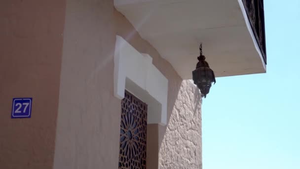 Декоративный восточный арабский фонарь с цветным стеклом украшает здание в городе. Улица в Марокко в полдень. Мусульманский месяц Рамадан — стоковое видео