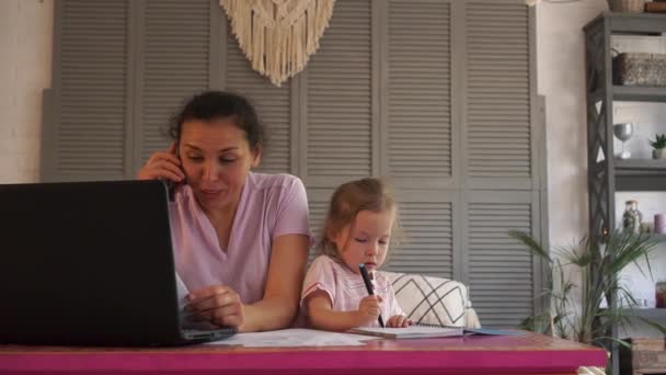 Mother working from home during COVID-19 pandemic with kids, little daughter, girl. A woman is talking on the phone. Remote work. Covid-19 lockdown — Stock Video