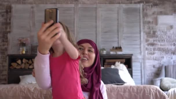 Happy smiling family muslim mother and daughter communicate via video link online on the Internet using a smartphone. Video chat. Social distancing, stay at home, lockdown during coronavirus — Stock Video