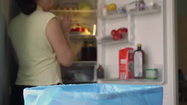 Tirando basura de comida a la basura. Pérdida de alimentos domésticos. El deterioro de los alimentos en el hogar se produce debido a un almacenamiento inadecuado. Una mujer arroja comida caducada sin comer del refrigerador — Vídeos de Stock