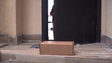 Bir anne ve çocuk kapıyı açar ve internet siparişlerini, online alışverişlerini ya da bağış yemek kutularını alırlar. Karton Kutu Paketi. Evin kapısına haber vermeden teslimat yapmak.
