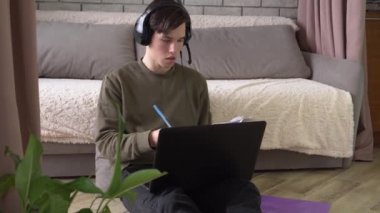 Kulaklık takan ve evde mikrofon dersi alan bir öğrenci. Uzaktan eğitim. Coronavirus Covid-19 tecrit sırasında uzaktan çalışma