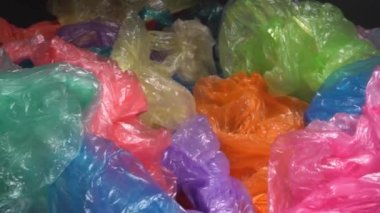 Bir sürü tek kullanımlık renkli plastik poşet büyük bir yığın halinde atılıyor. Plastik Paketleme Kirliliği. Çöp sahalarındaki plastik çöpler ve okyanus