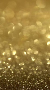 Altın Parıltı Arkaplanı. Sihirli toz, parlak doku, tatil ışıkları, uçan parçacıklar güzel bir bokeh oluşturur. Parlak Noel arkaplanı. Dikey