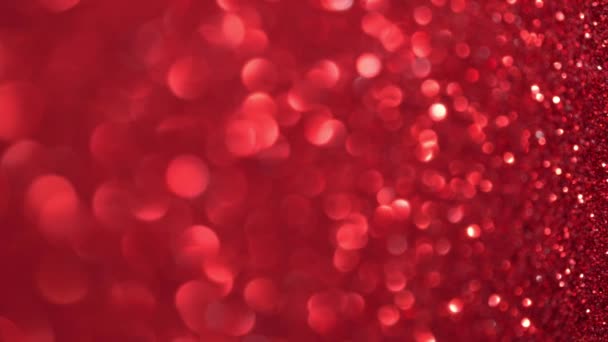 赤いグリッターの背景。魔法のほこり、光沢のある質感、休日の光、飛行粒子は美しいボケを形成します。輝くクリスマスの背景。垂直ビデオ — ストック動画