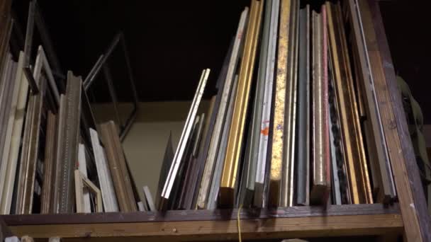 Um rack de prateleira com pinturas em estúdio de artista. Velhas telas e molduras em uma prateleira no estúdio de artistas — Vídeo de Stock