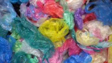 Bir sürü tek kullanımlık renkli plastik poşet büyük bir yığın halinde atılıyor. Plastik Paketleme Kirliliği. Çöp sahalarındaki plastik çöpler ve okyanus