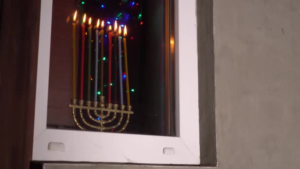 Chanuka w Izraelu. Zapalanie Å wiec, ktÃ ³ re sÄ przechowywane w menorah lub hanukkiyah. Dziewięć świeczników z zapalonymi światłami na oknie wieczorem. Żydowskie wakacje — Wideo stockowe