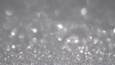 Hareket eden ve titreşen parçacıkları olan soyut gümüş parıltılı arka plan. Sihirli toz, metalik pullar, parlak doku, tatil ışıkları, uçan parçacıklar güzel bir bokeh oluşturur. Parlayan Noel arkaplanı