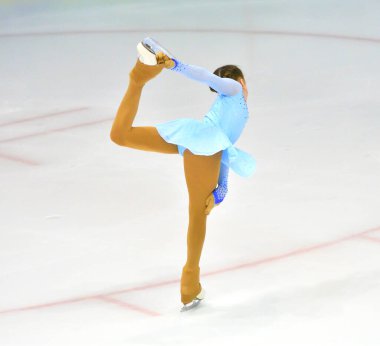 Kız artistik buz pateni pistinde suni buz ile yuvarlanıyor.