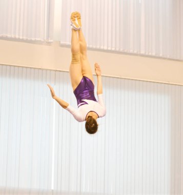 Kızlar trambolinde antrenman yapar, durgun bir odada zıplar.