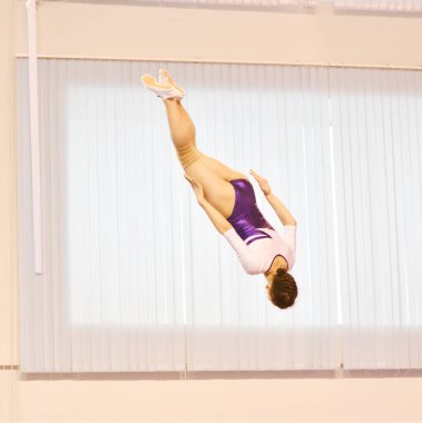 Kızlar trambolinde antrenman yapar, durgun bir odada zıplar.