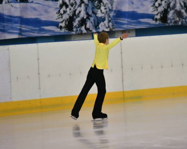 Erkek artistik buz pateni pistinde yapay buz ile yuvarlanıyor.