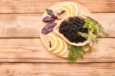 Kesme tahtasında taze bitkiler olan siyah havyar. 