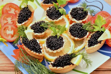 Siyah havyarlı turtalar ve taze yeşillikler. 