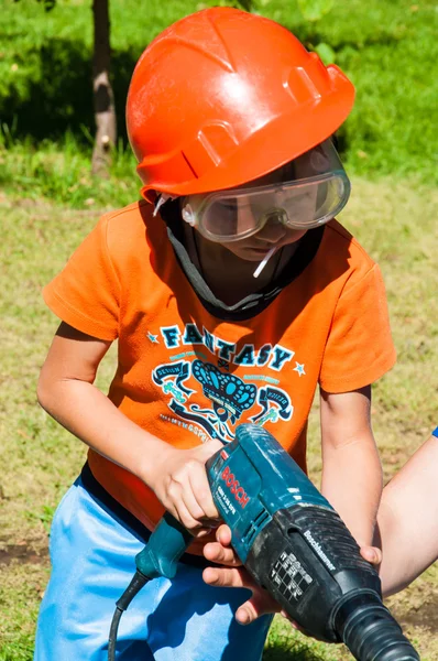 Un niño aprende a trabajar con taladro eléctrico —  Fotos de Stock