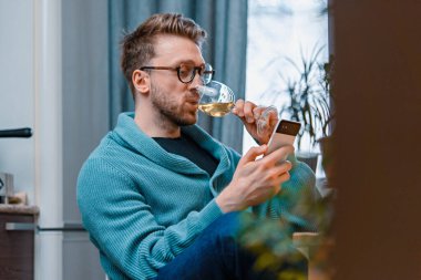 Adam arkadaşlarıyla video aracılığıyla konuşuyor ve şarap içiyor. Çevrimiçi Tarih, Arkadaşlarla Çevrimiçi Buluşma. Evde kal. Sosyal Mesafe ve Tecrit.