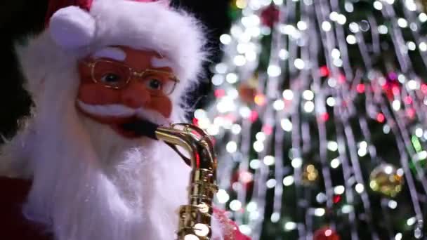 Modello di Babbo Natale che tiene e gioca a sassofono e ornamenti natalizi sull'albero di Natale — Video Stock