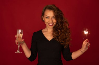 Şampanya ve maytaplı genç bayan kameraya bakıyor, kırmızı arka plan.