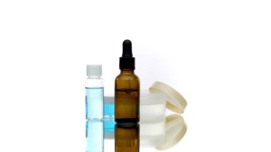 Kozmetik şişe sıvıları beyaz arka planda dönüyor, vücut yağı doğal kremi.