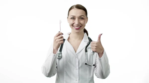 섹시 한 의사가 칫솔을 들고 엄지손가락을 위로 올려 놓은 간판처럼 생긴 쇼를 한다 — 스톡 사진