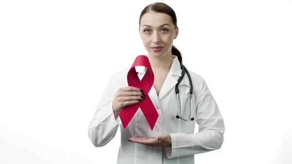 Sonriente hermosa doctora mostrando AID, cinta roja del VIH sobre fondo blanco —  Fotos de Stock