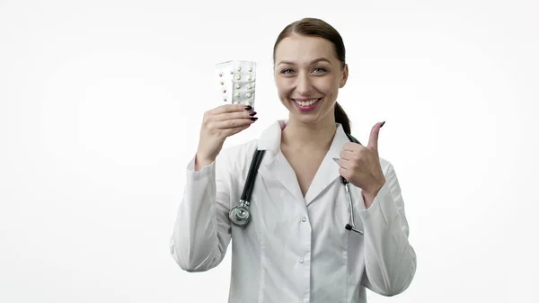 Lächelnder Arzt zeigt zwei Pillen-Blasen und ähnliches Zeichen mit erhobenem Daumen — Stockfoto