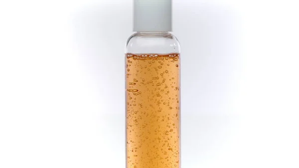Conjunto de cuidados com a pele, recipiente transparente com líquido girando sobre fundo branco — Fotografia de Stock