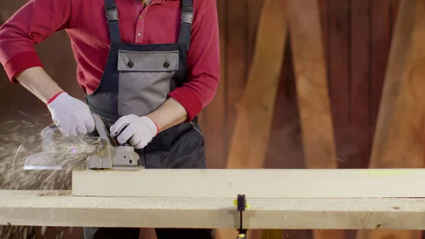 Close-up hands of carpenter in overalls polish surface of blank with planer — Stock Photo, Image