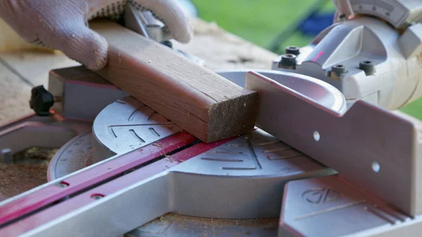 Tischler stellt Gehrungssägenwinkel von 30 Grad ein und schneidet Holzwerkstück diagonal — Stockfoto