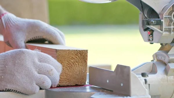 Tischler setzt Holzwerkstück präzise in die Gehrungssäge und bohrt die Stange — Stockfoto