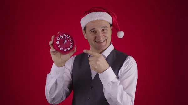 El hombre alegre en el sombrero de Santa señalando el reloj recuerda Minutos antes de Nochevieja — Foto de Stock