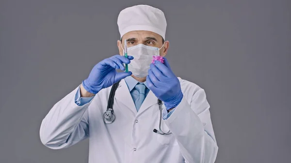 Middle aged doctor holds syringe, injects test vaccine in covid-19 virus cell — Stock Photo, Image