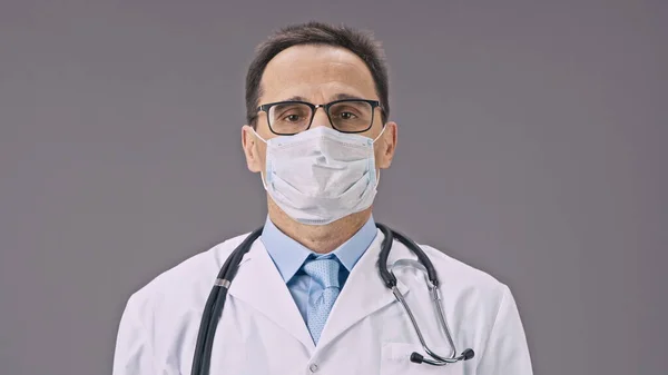 Médico atraente tira máscara protetora contra covid-19, sorrisos felizes — Fotografia de Stock