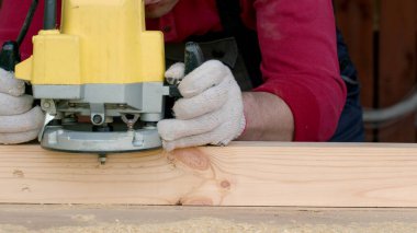 Csucasian marangozu ahşap kirişi değirmen makinesiyle işliyor..