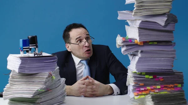 Office worker sits at desk looks on piles of paperwork with fear — Stock Photo, Image