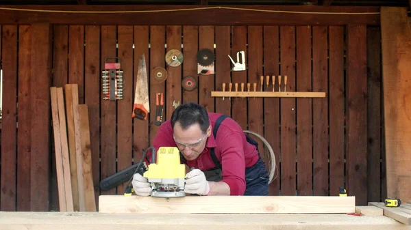 Travailleur du bois traite le bois avec une fraiseuse dans son atelier de menuiserie — Photo