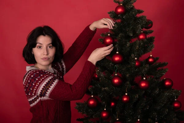 Mujer bonita joven en jersey de punto con adorno decorando árbol de Navidad — Foto de Stock