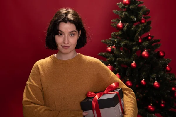 Mujer bonita sosteniendo regalos de Navidad mira con sonrisa a la cámara, regalos conscientes — Foto de Stock