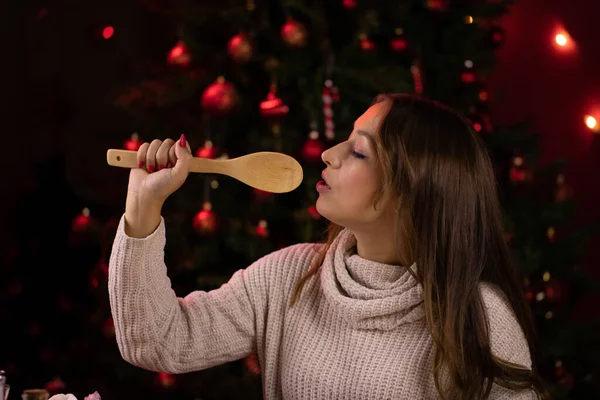 Linda chica canta usando espátula en lugar de micrófono en el telón de fondo del árbol de Navidad — Foto de Stock