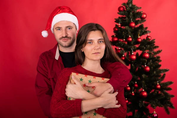 Preciosa pareja joven posando en casa frente al árbol de Navidad, vacaciones familiares de invierno — Foto de Stock