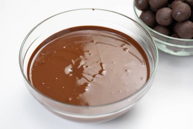 Yakından bakınca, cam kasede erimiş siyah çikolata, izole edilmiş beyaz arka plan. Yer mantarları