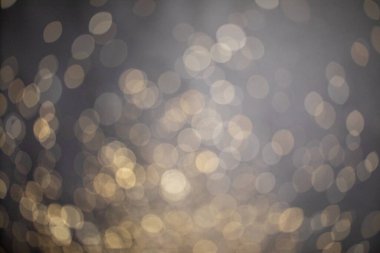 Altın rengi ışıltı tozu arka planda bulanıklık, odaklanmış koyu renkli doku